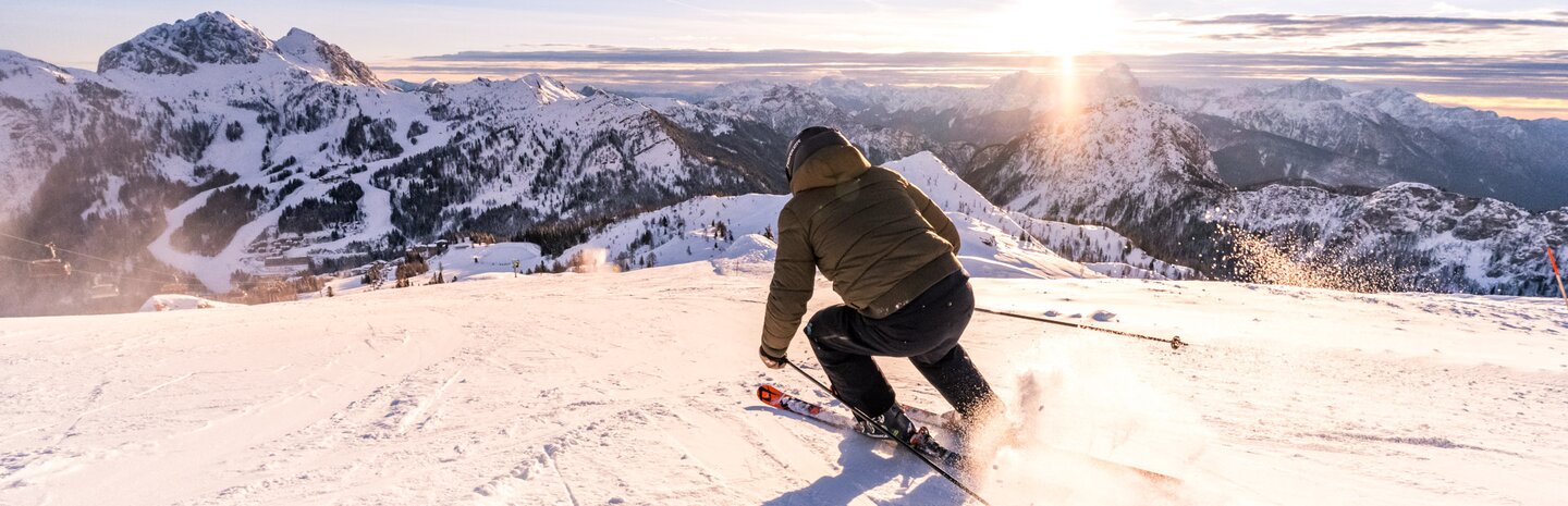 Skifahrer auf Skipiste mit Bergpanorama im Hintergrund