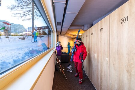 Skifahrer schauen beim Fenster direkt auf die Piste vom Skikeller aus