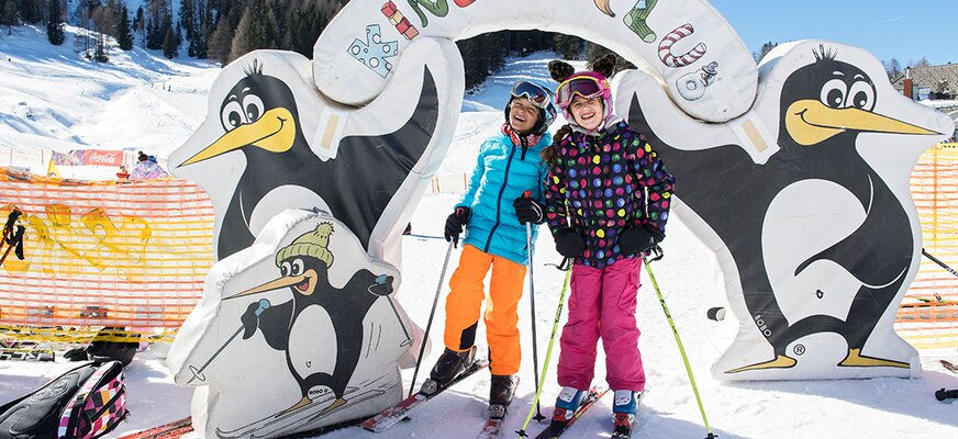 Zwei Kinder auf den Skiern vor einem Tor zum Kinderclub