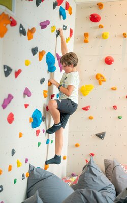 Kind bouldert auf der Boulderwand