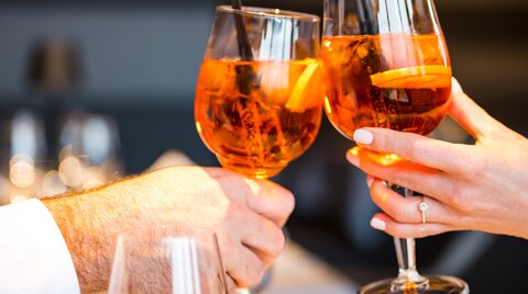 Personen stoßen mit zwei Gläsern Aperol an