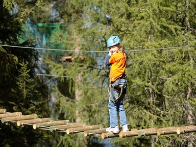 Kind balanciert auf Leiter im Hochseilgarten