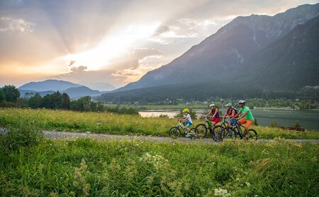 Familie auf den Mountainbiker beim Sonnenuntergang entlang des Sees