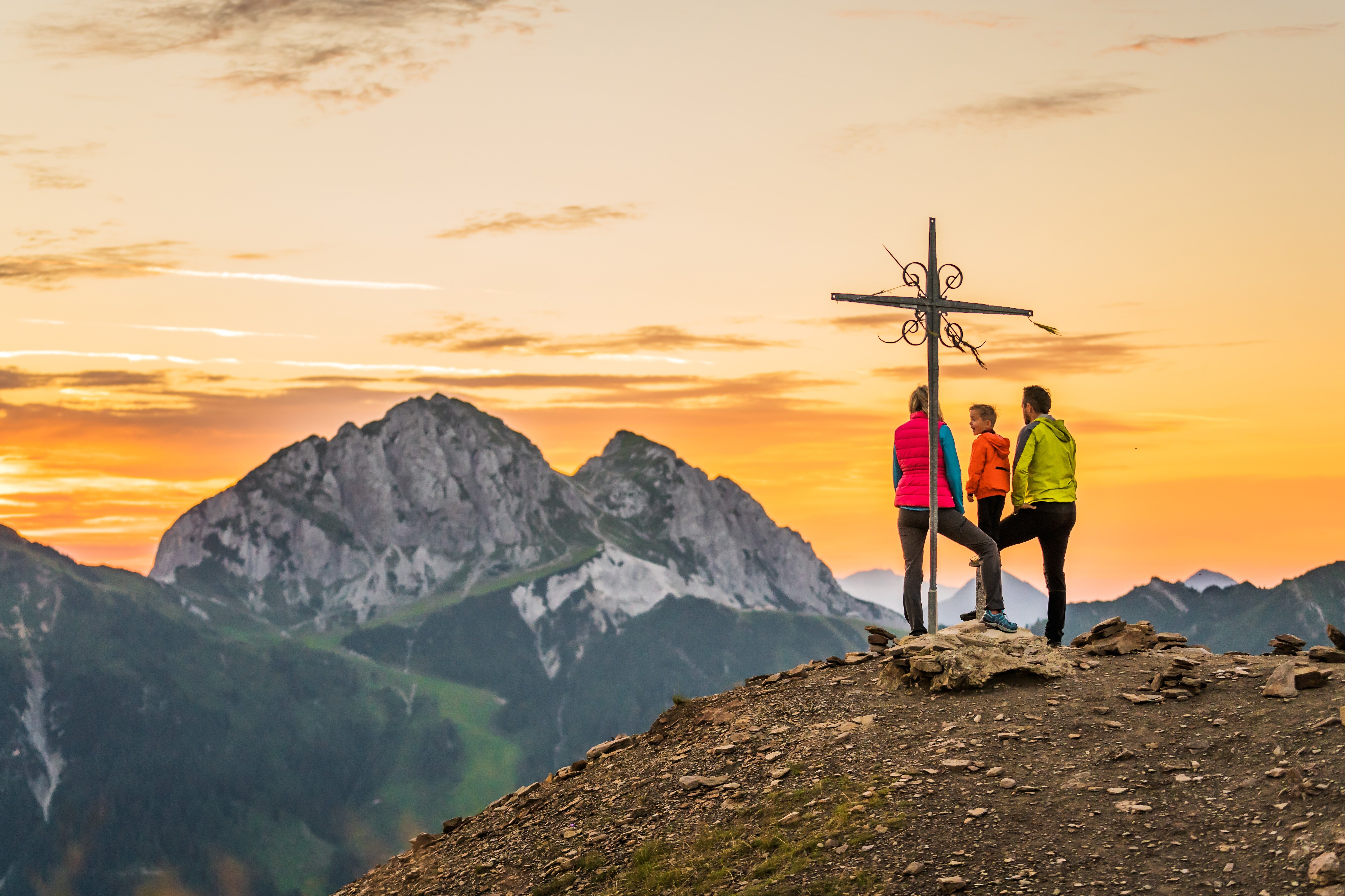 Familie bei Sonnenuntergang am Gipfelkreuz