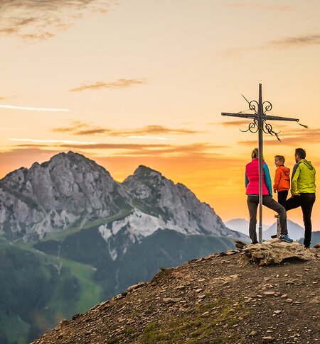 Familie bei Sonnenuntergang am Gipfelkreuz