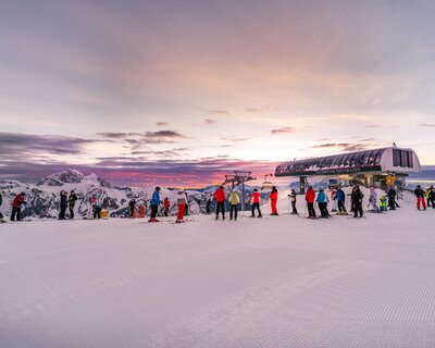 Skifahrer auf der Piste mit Blick auf den Sonnenaufgang