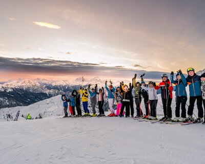 Skifahrer auf der Piste mit Blick auf den Sonnenaufgang