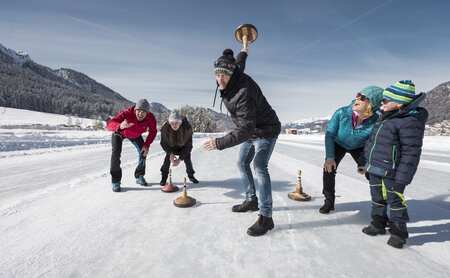 Familie und Freunde beim Eisstockschiessen am Weissensee