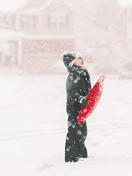 Kind mit Rodel im Schnee