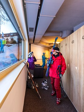 Skifahrer schauen beim Fenster direkt auf die Piste vom Skikeller aus