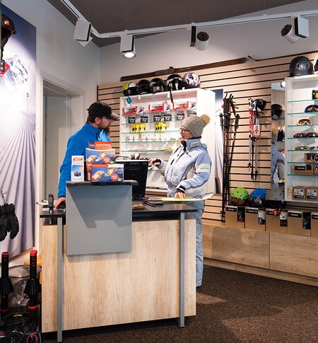 Frau lässt sich im Skishop von einem Mitarbeiter beraten.